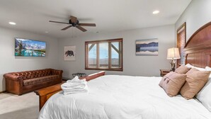 A bedroom with a large bed, a ceiling fan, a window with blinds, and artwork on the walls. - Breathtaking 2-Level Mountain Retreat (Blowing Rock)