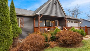 A two-story house with a grey exterior, a wooden porch, and a garage. - Breathtaking 2-Level Mountain Retreat (Blowing Rock)