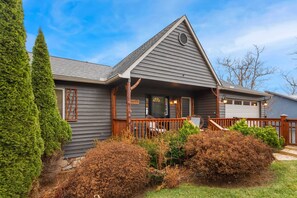 A two-story house with a grey exterior, a wooden porch, and a garage.