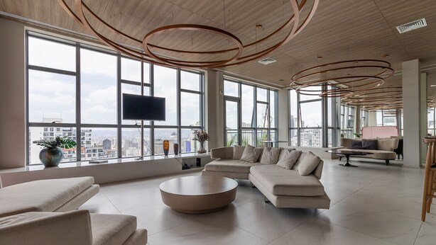 Un salón amplio con ventanas grandes, un diseño moderno de techo y una distribución de asientos confortable.