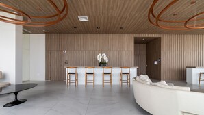 Una zona de recepción moderna con un sofá blanco curvo, una mesa negra y sillas de madera.