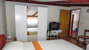 A bedroom with a bed, a wardrobe, a television on a small table, and a door leading to another room. - 2 Bed Flat - Sleeps 8 - Parking - Wifi (Novalja)