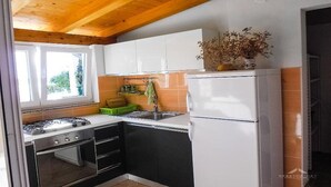 A compact kitchen with a gas stove, oven, and a refrigerator. - 2 Bed Flat - Sleeps 8 - Parking - Wifi (Novalja)