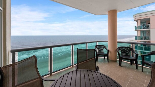 A balcony with a view of the ocean, featuring a table and chairs. - Luxurious Oceanfront Penthouse with Private Glass-Walled Balcony | Crescent Keyes - PH 9 (North Myrtle Beach)