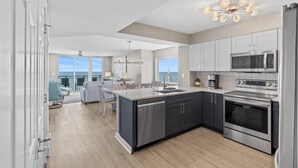 A modern kitchen with stainless steel appliances, a central island, and a view to the outside.