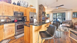 A modern kitchen with wooden cabinets, stainless steel appliances, and a central island with bar stools.
