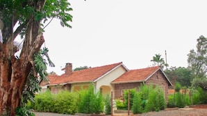 A two-story house with a red-tiled roof, surrounded by lush greenery and a gravel driveway. - Celio Jardine Lavington (Nairobi)