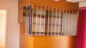 A corner room with a wooden cabinet and a red curtain. - Celio Jardine Lavington (Nairobi)