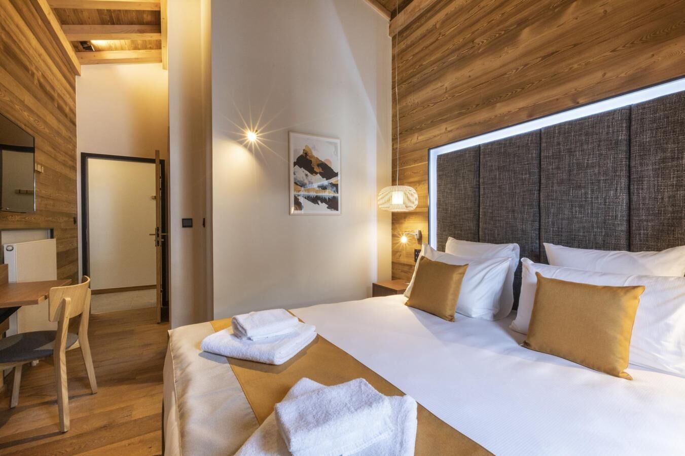 Una camera d'albergo con un letto grande, una scrivania e una sedia.