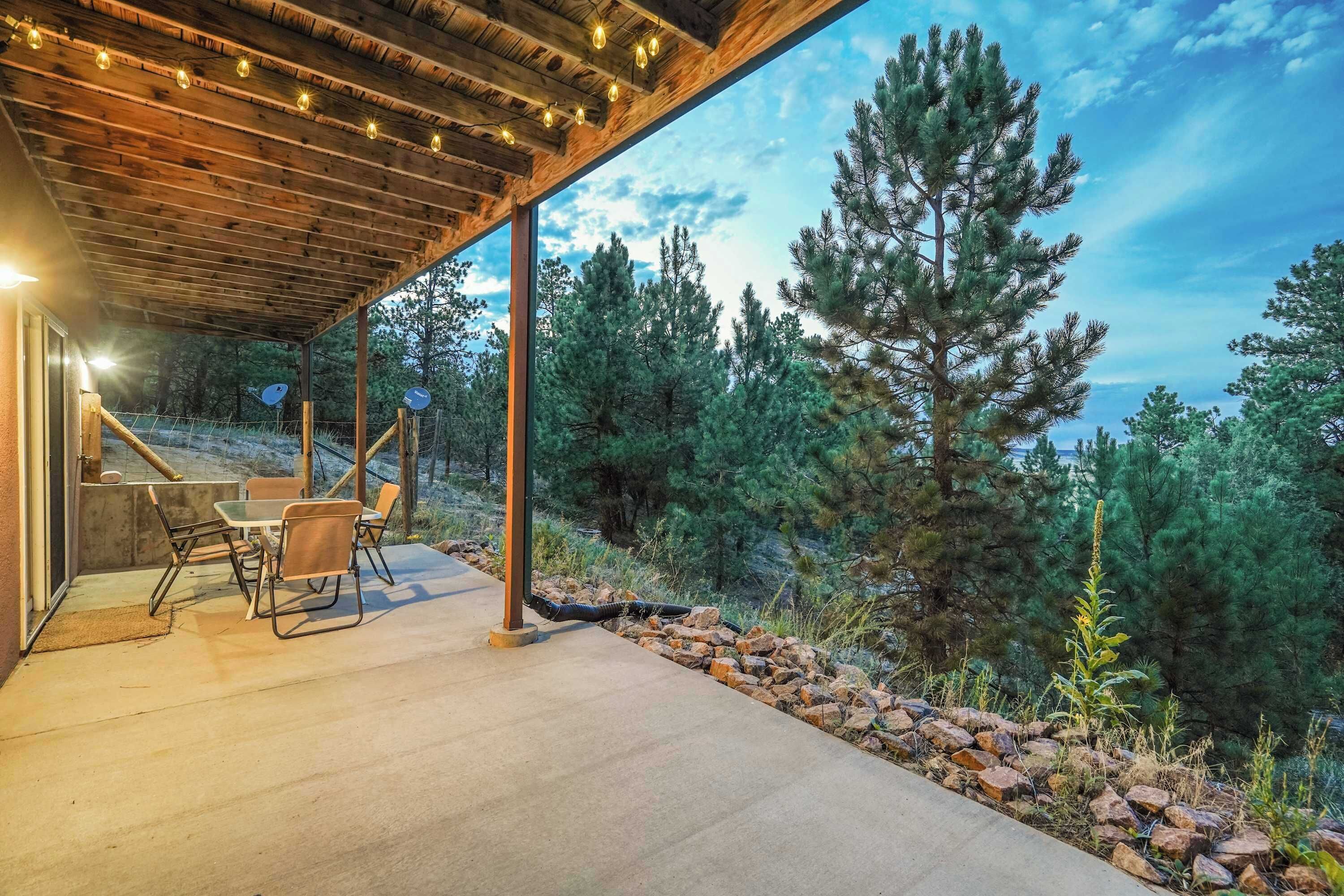 Eine Terrasse im Freien mit Tisch und Stühlen, umgeben von einer Holzpergola und Lichterketten.
