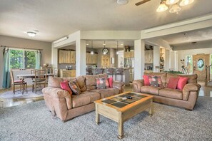 A spacious living room with two leather sofas, a coffee table, and a dining area with chairs and a table. - Nature's Oasis, 4BD Ranch Retreat, Hot tub! (Peyton)