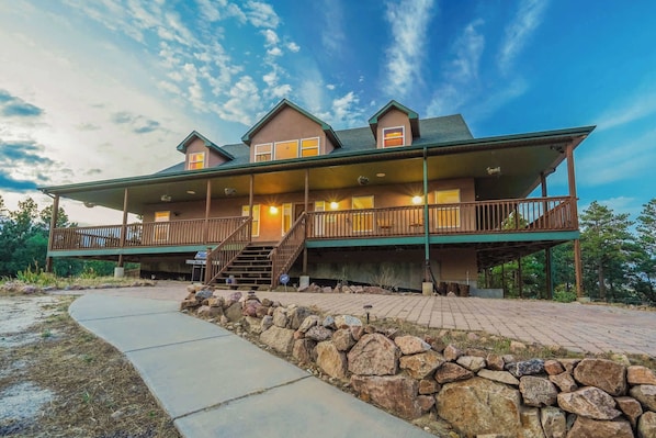 A large, two-story house with a covered porch and a stone retaining wall.