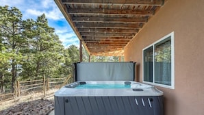 Ein Whirlpool unter einer hölzernen Pergola, ein Kiesweg und Blick auf Bäume.