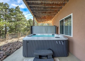 A hot tub with a wooden pergola overhead, a stone pathway, and a view of trees. - Nature's Oasis, 4BD Ranch Retreat, Hot tub! (Peyton)