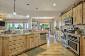 A modern kitchen with wooden cabinets, stainless steel appliances, and pendant lighting. - Nature's Oasis, 4BD Ranch Retreat, Hot tub! (Peyton)