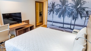 Une chambre d’hôtel avec un lit, un bureau avec une télévision et une porte donnant sur une salle de bain.