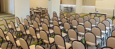 A conference room with rows of chairs, tables, a whiteboard, and a projector.