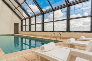 Una piscina techada, sillones reclinables de piscina