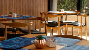 Un comedor moderno con mesas y sillas de madera, individuales azules y pequeñas macetas.
