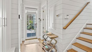 A hallway with white paneled walls, a wooden staircase, and a door leading to an outdoor area. - Beach Access and Private Pool (Watersound)