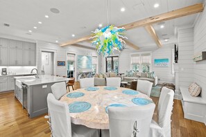 A spacious kitchen with a central island, wooden beams, and a modern chandelier.