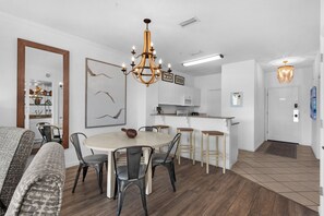 A modern kitchen with white cabinets, a microwave, and a coffee machine.