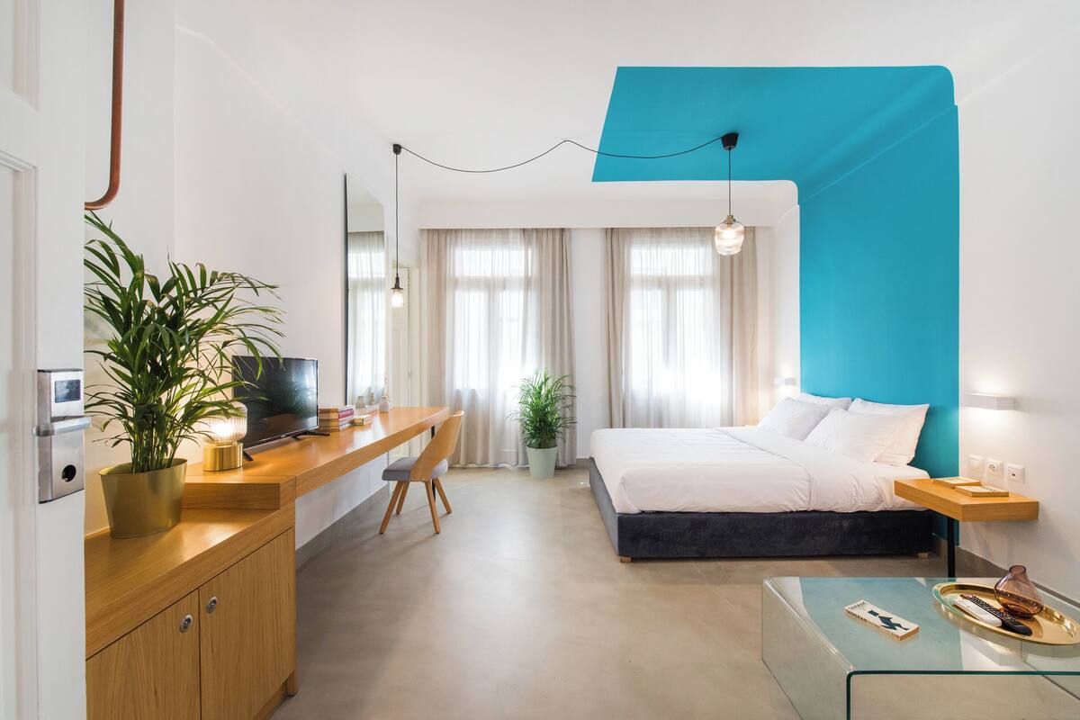A modern hotel room with a bed, desk, and seating area.