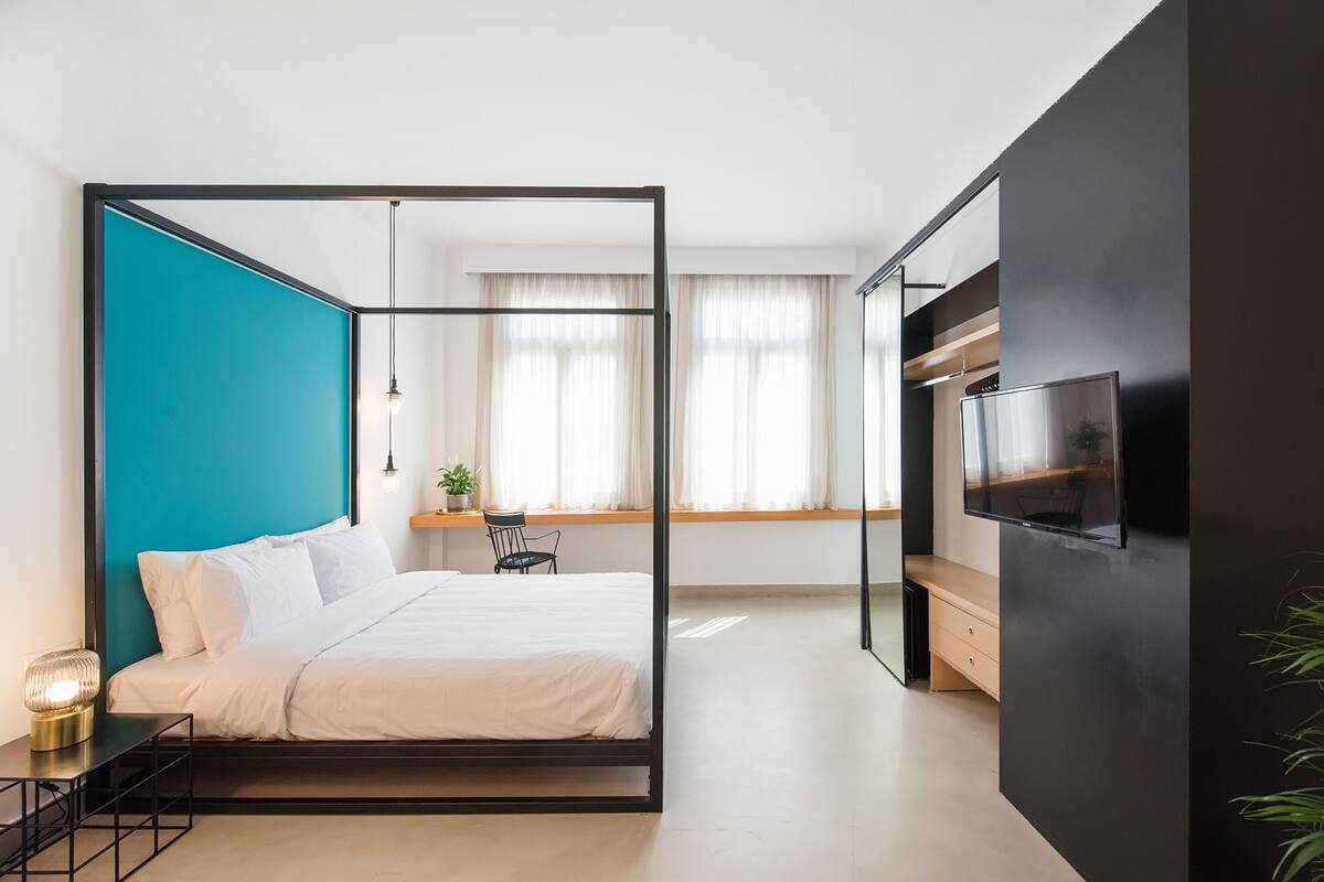 A modern bedroom with a bed, a desk, and a TV.