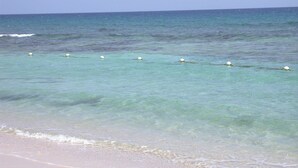Ein Strand mit klarem türkisblauem Wasser und einem sandigen Ufer.