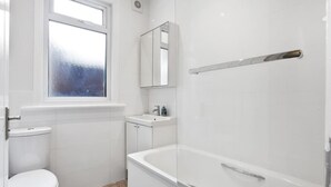 A bathroom with a toilet, sink, mirror, and shower. - Modern 2 bed in Wembley - 30 min to central London (Greater London)