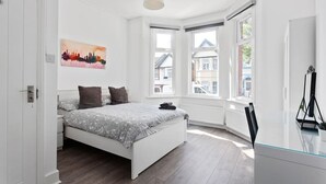 A bedroom with a bed, a painting, and large windows. - Modern 2 bed in Wembley - 30 min to central London (Greater London)