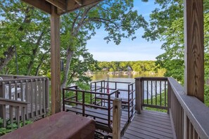 A wooden deck with a view of a lake and a house in the background.