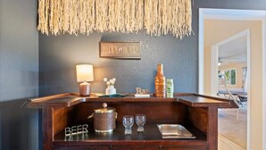 A bar area with a 'HAPPY HOUR' sign, a beer tap, a bottle, glasses, and a lamp. - The Anchor House — Experience lakeside luxury at a spacious 5-bedroom retreat in Osage Beach. Enjoy breathtaking views, modern comforts, and direct lake access for the perfect Lake of the Ozarks getaway. (Osage Beach)