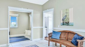 A room with a wooden bench, a door leading to another room, a window, and a painting on the wall. - Peaceful Waterfront Pool Home 3 Bedroom Home by RedAwning (Palm Coast)