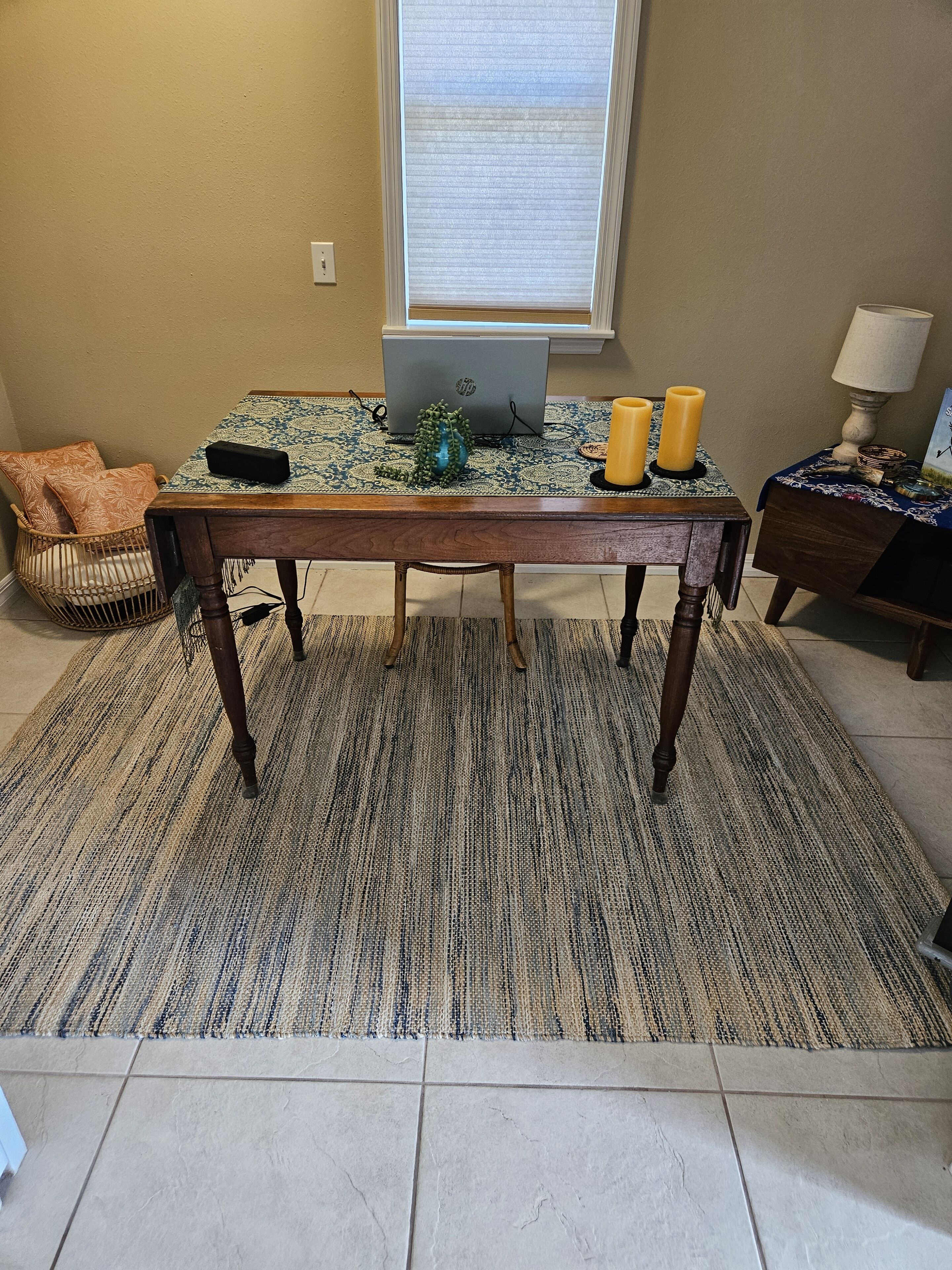 A dining area with a wooden table, patterned tablecloth, and candles.