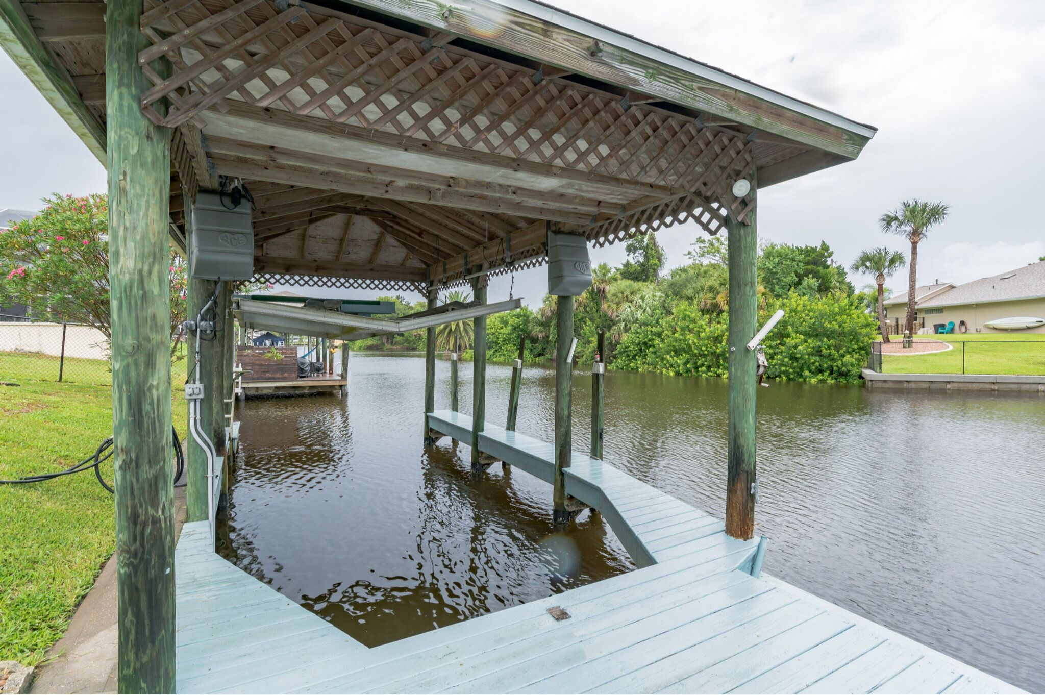 A covered wooden dock extending over a body of water, with a gazebo structure above.