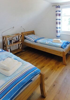 Cozy bedroom with two beds, a nightstand, and a window with a striped curtain.