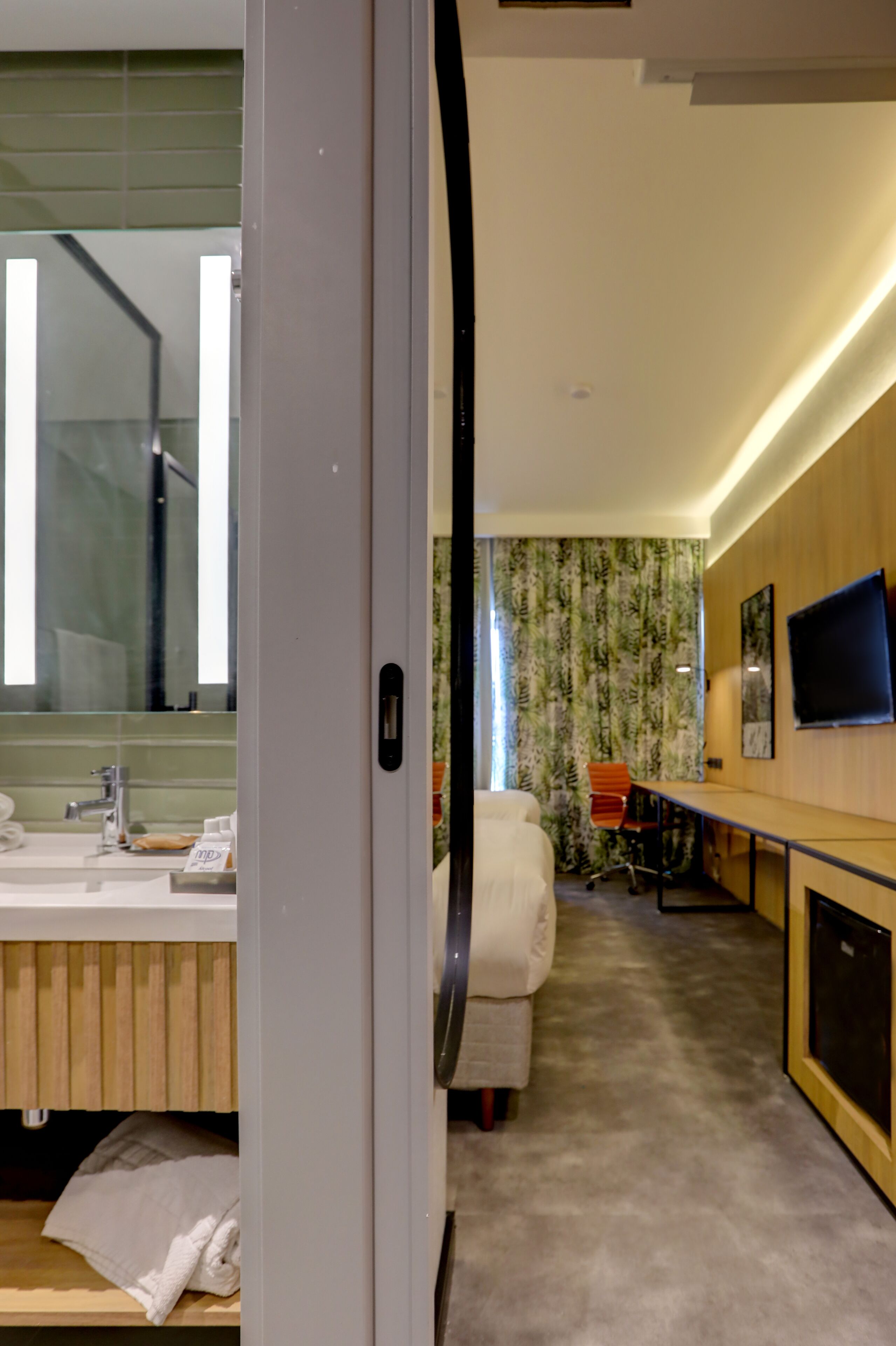 Habitación de hotel con baño, cama, escritorio y televisor.