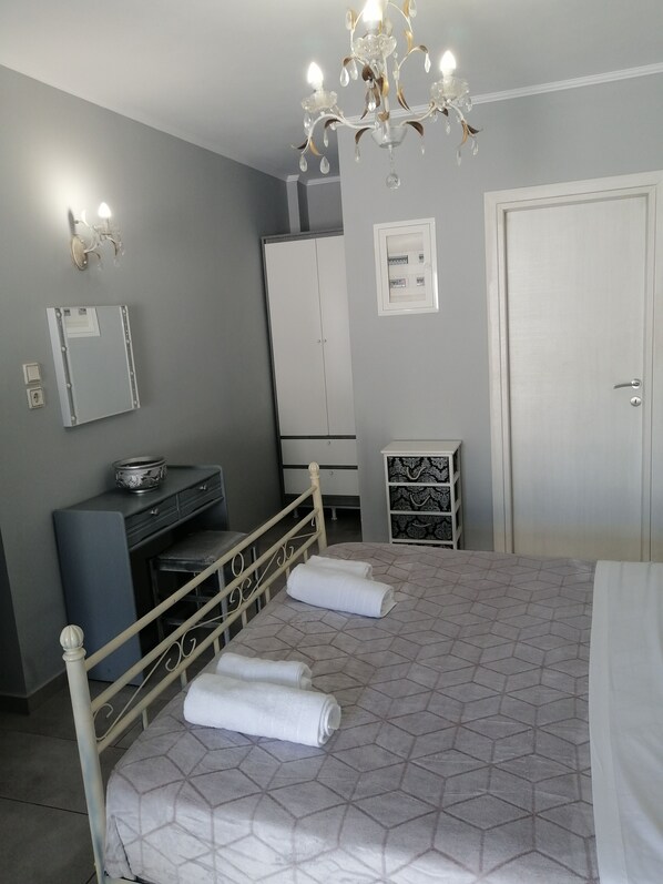 A bedroom with a bed, a wardrobe, a desk, and a chandelier.
