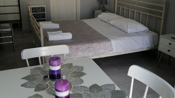 Ein Schlafzimmer mit einem Bett, Nachttischen, einer Chandelüster und einem Tisch mit Kerzen und einer dekorativen Tischläufer.