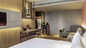 Une chambre d’hôtel moderne équipée d’un lit, d’un bureau, d’une chaise, d’un canapé et d’une armoire.