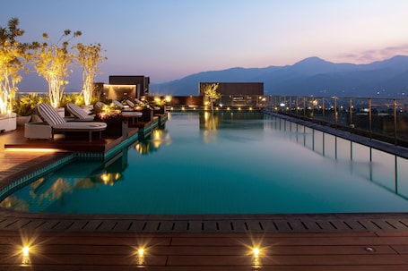 Una piscina al aire libre, sombrillas, sillones reclinables de piscina