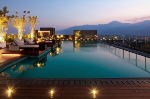Una piscina al aire libre, sombrillas, sillones reclinables de piscina