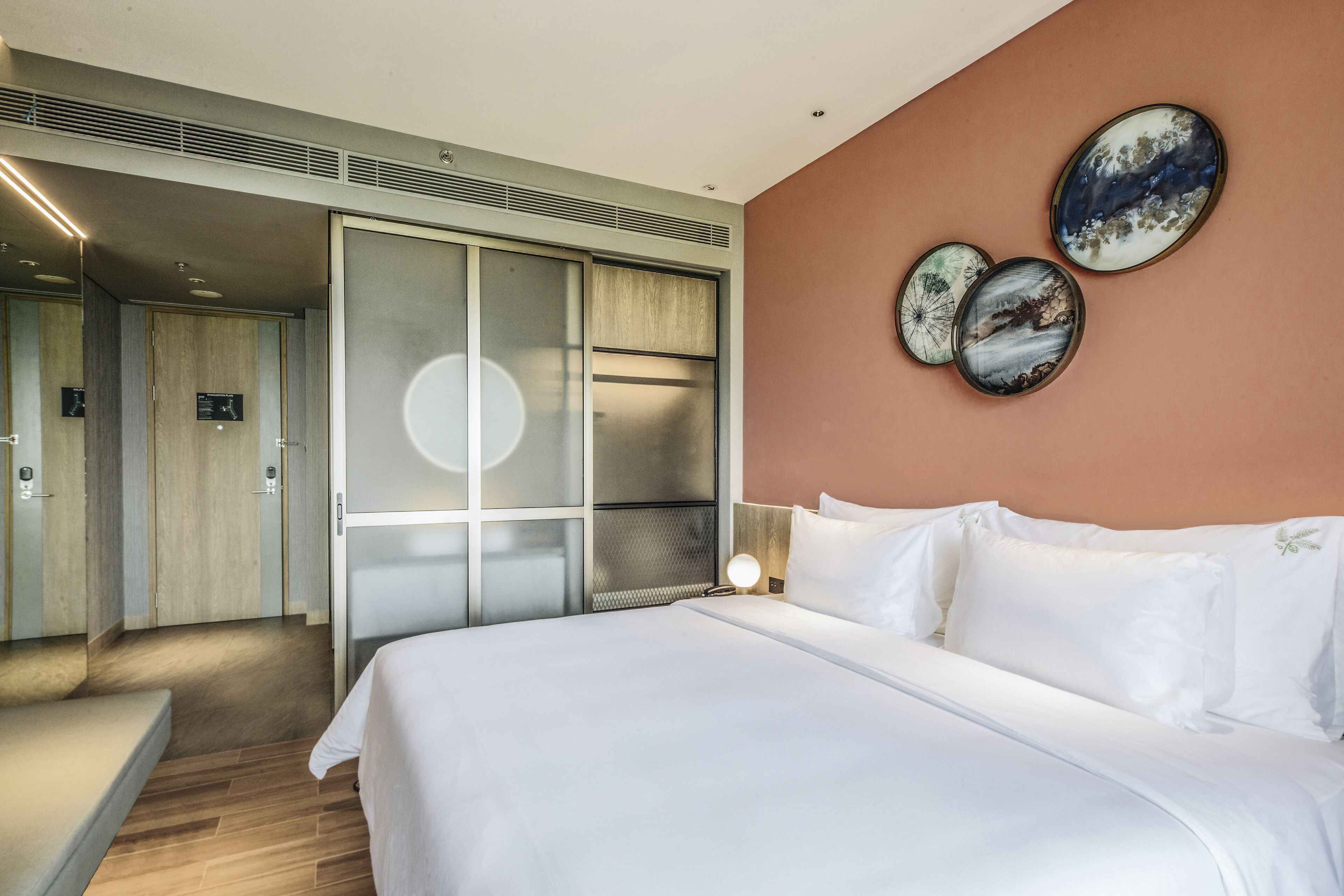 A hotel room with a bed, a nightstand, a wall-mounted lamp, and a sliding door closet.