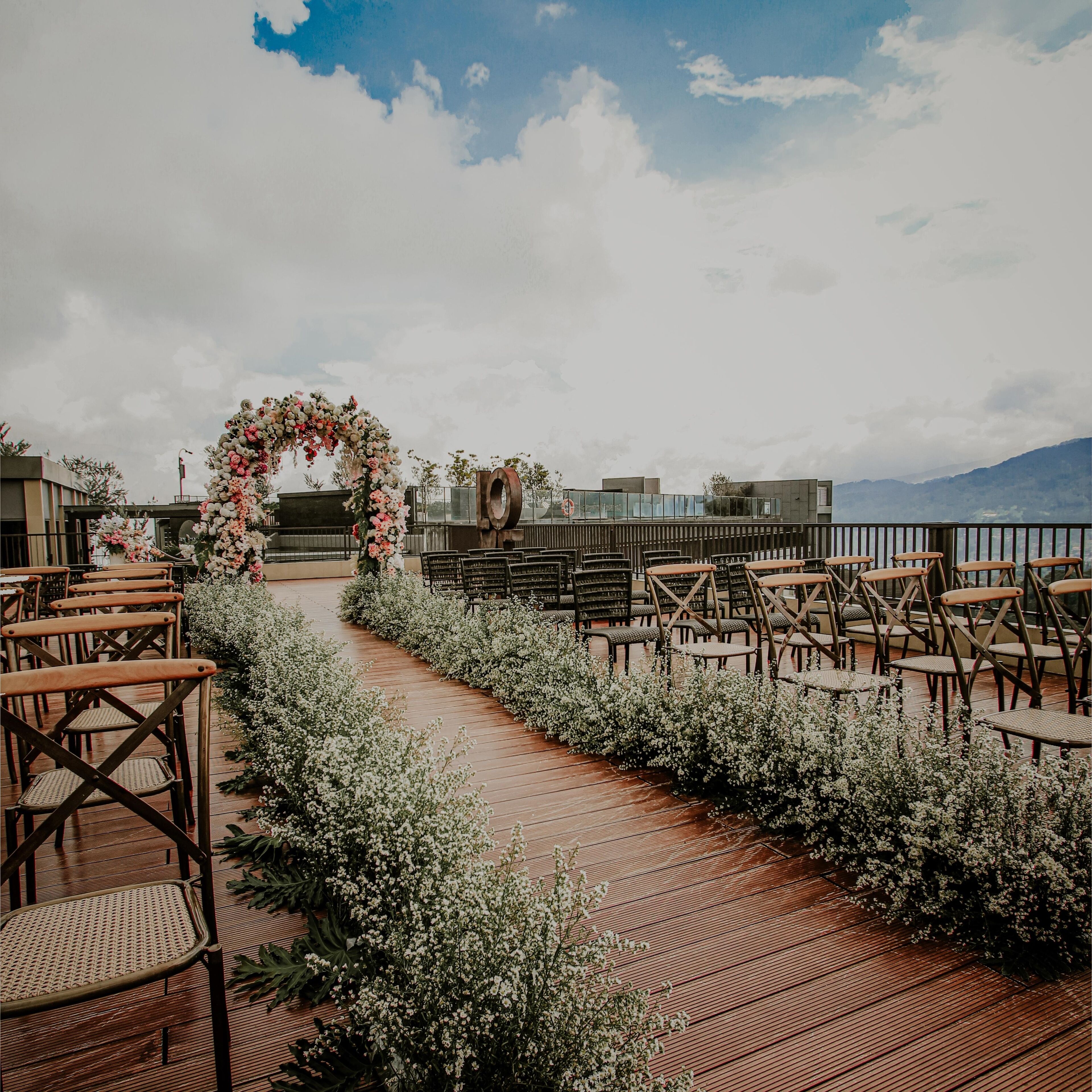 An outdoor wedding aisle with floral decorations and wooden chairs.