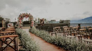 An outdoor wedding aisle with floral decorations and wooden chairs.