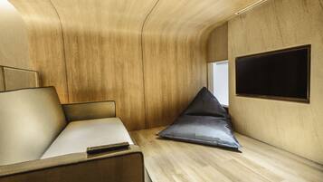 Ein modernes Interieur mit Holzbalkendecke, einem Bett mit Kissen, einem kleinen Tisch und einem an der Wand befestigten Fernseher.