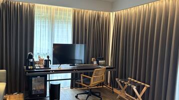Una habitación de hotel moderna con un escritorio de madera, un televisor de pantalla plana, una cafetera y una silla.