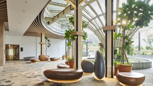 Eine moderne Lobby mit geometrisch gemustertem Boden, zeitgenössischer Sitzmöbeln und großen Fenstern, die für natürliches Licht sorgen.