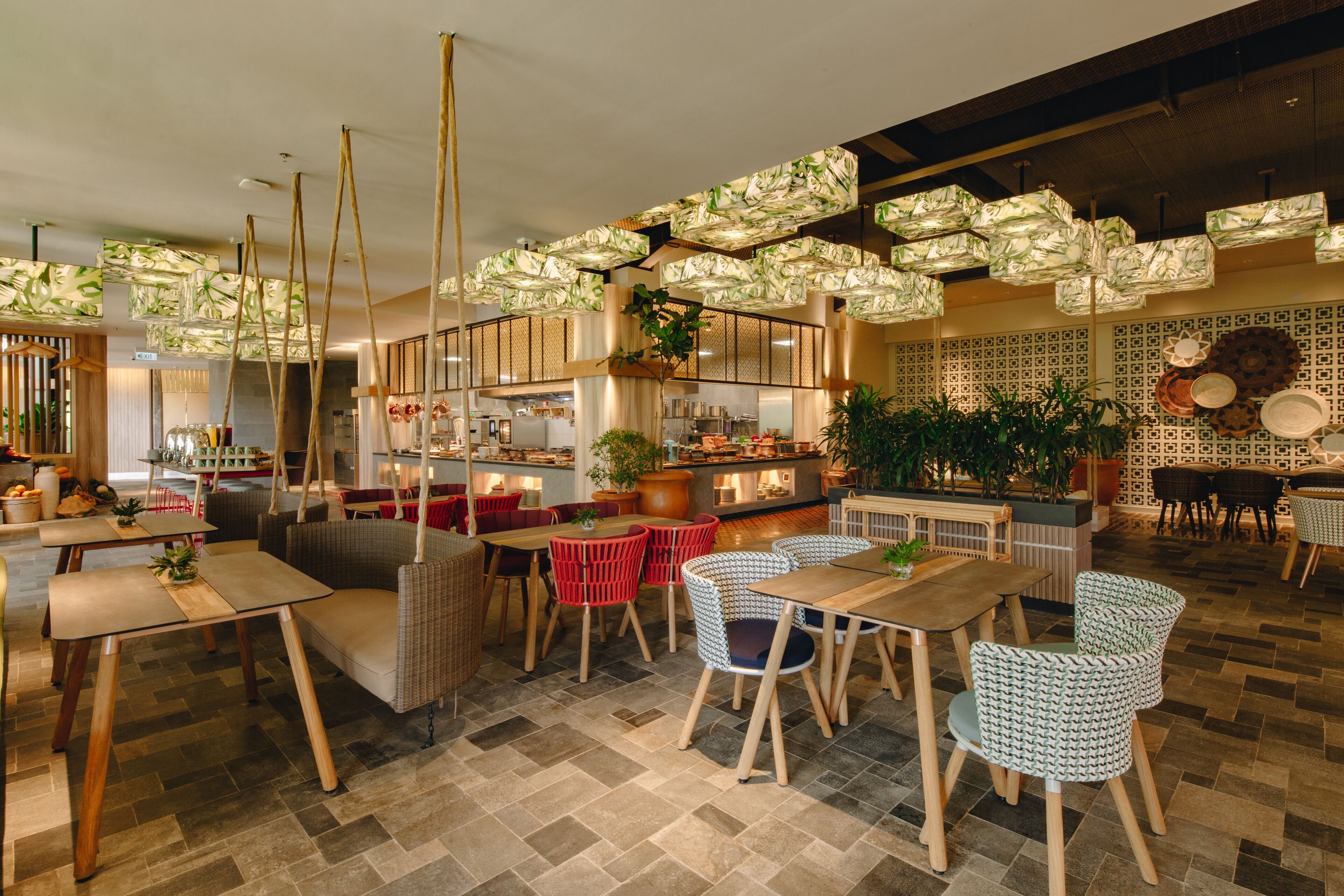 A modern restaurant interior with wooden tables and chairs, hanging paper lanterns, and patterned wall decor.